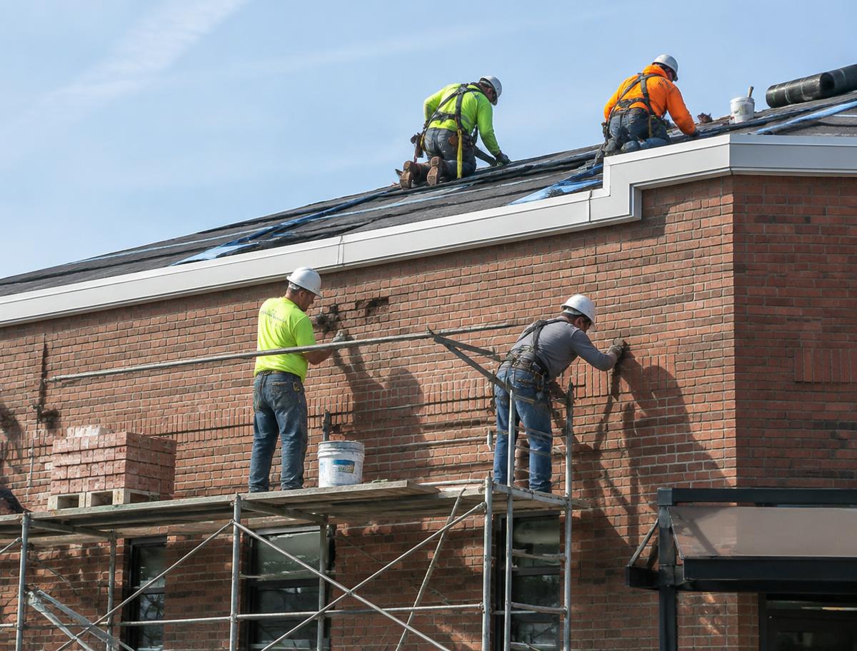 Crew performing roofing and masonry repairs on a commercial building